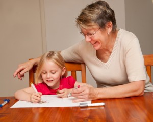 A little girl drawing with her carer